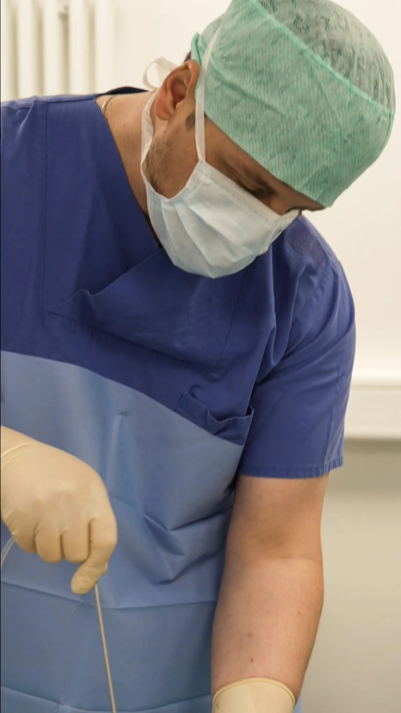 Dr. (univ. Te.) Nusret Fetai setzt eine feine Naht im Operationssaal, präzise Wundversorgung in der Ästhetischen Chirurgie, Düsseldorf