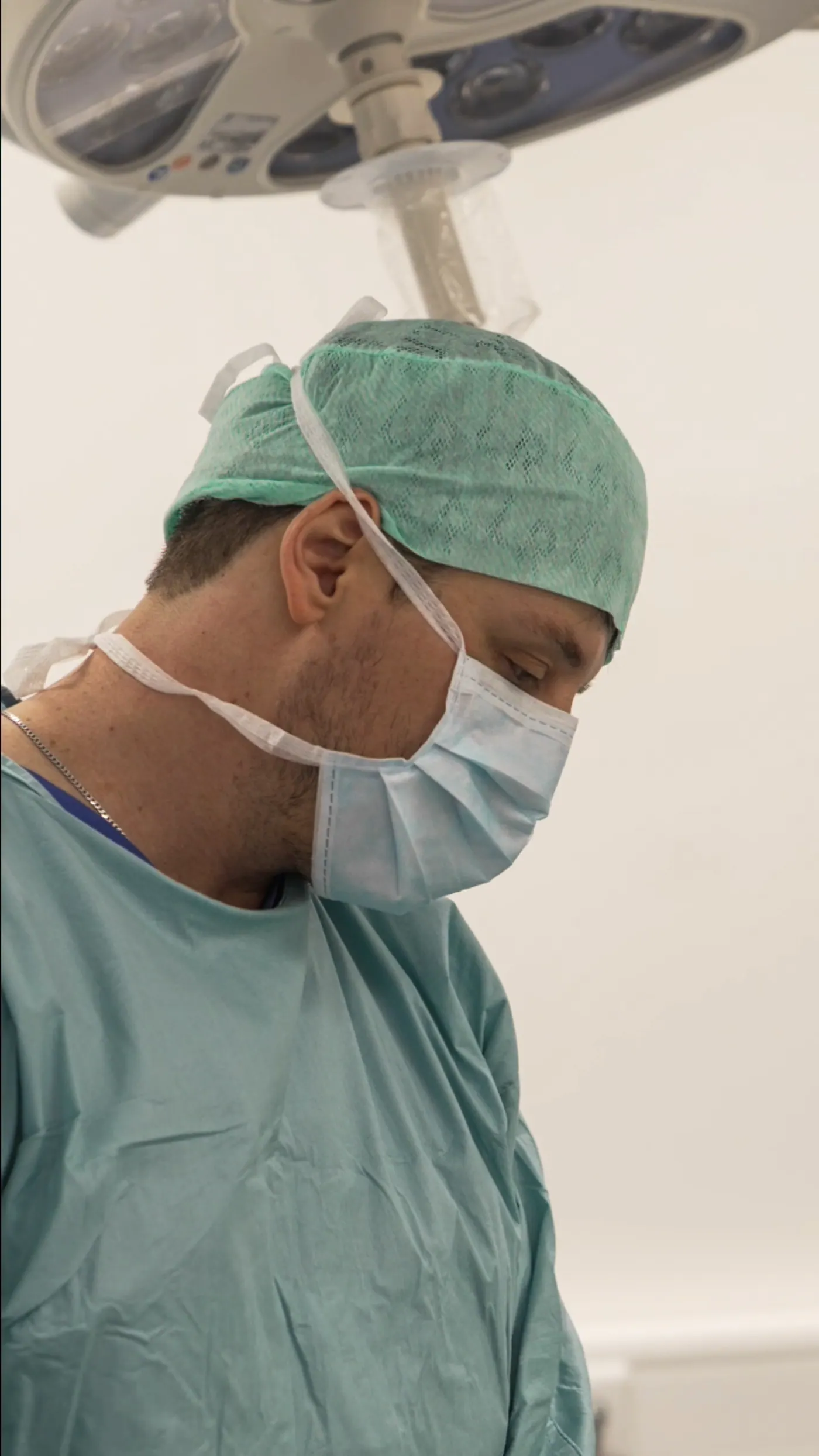Dr. (univ. Te.) Nusret Fetai konzentriert unter der Operationsleuchte im OP, Ästhetische Chirurgie in Düsseldorf
