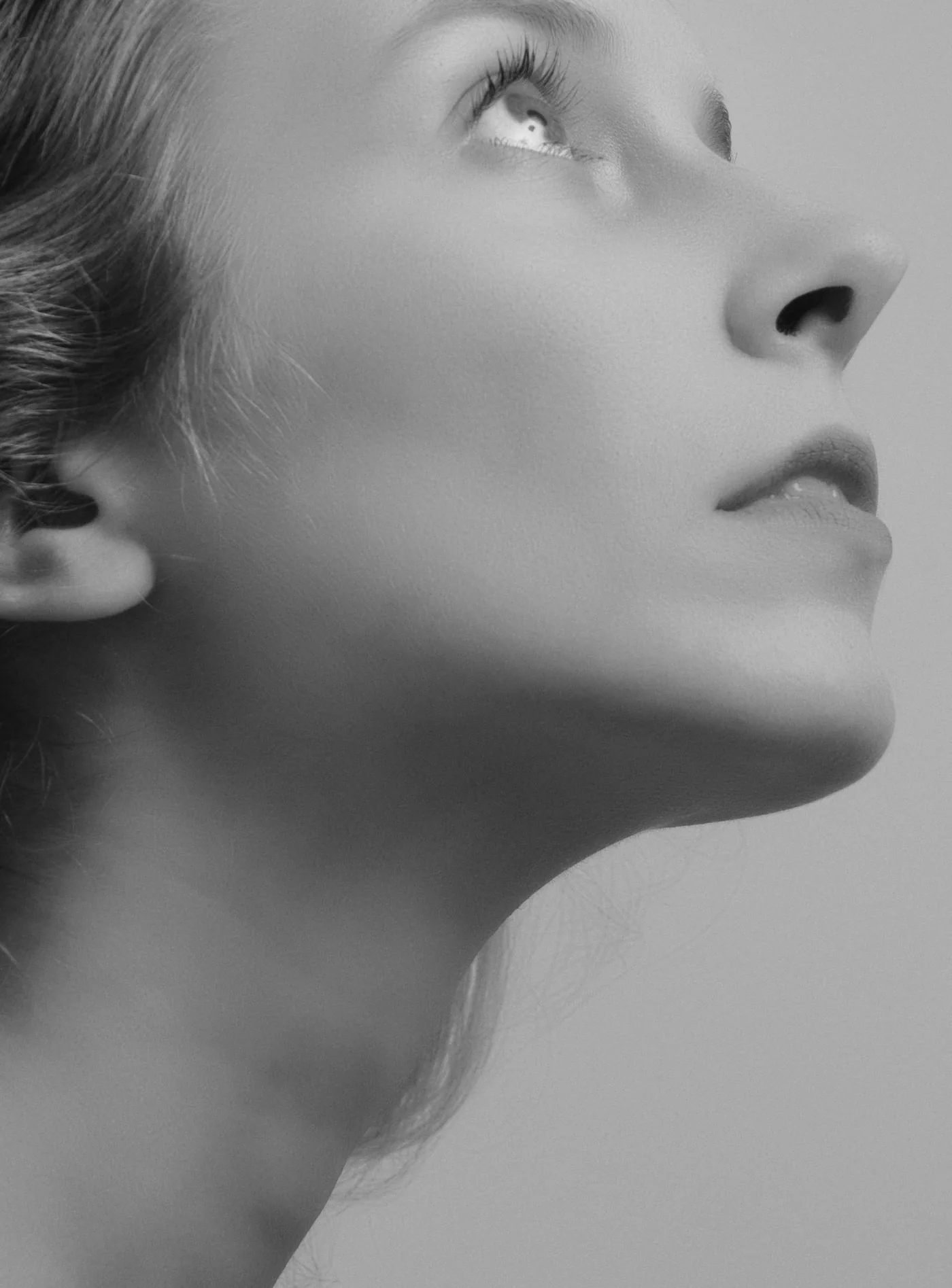 Schwarzweiß Profil einer Frau mit erhobenem Kinn, klare Hals und Kinnlinie, Modellaufnahme zum Neck Lift in Düsseldorf