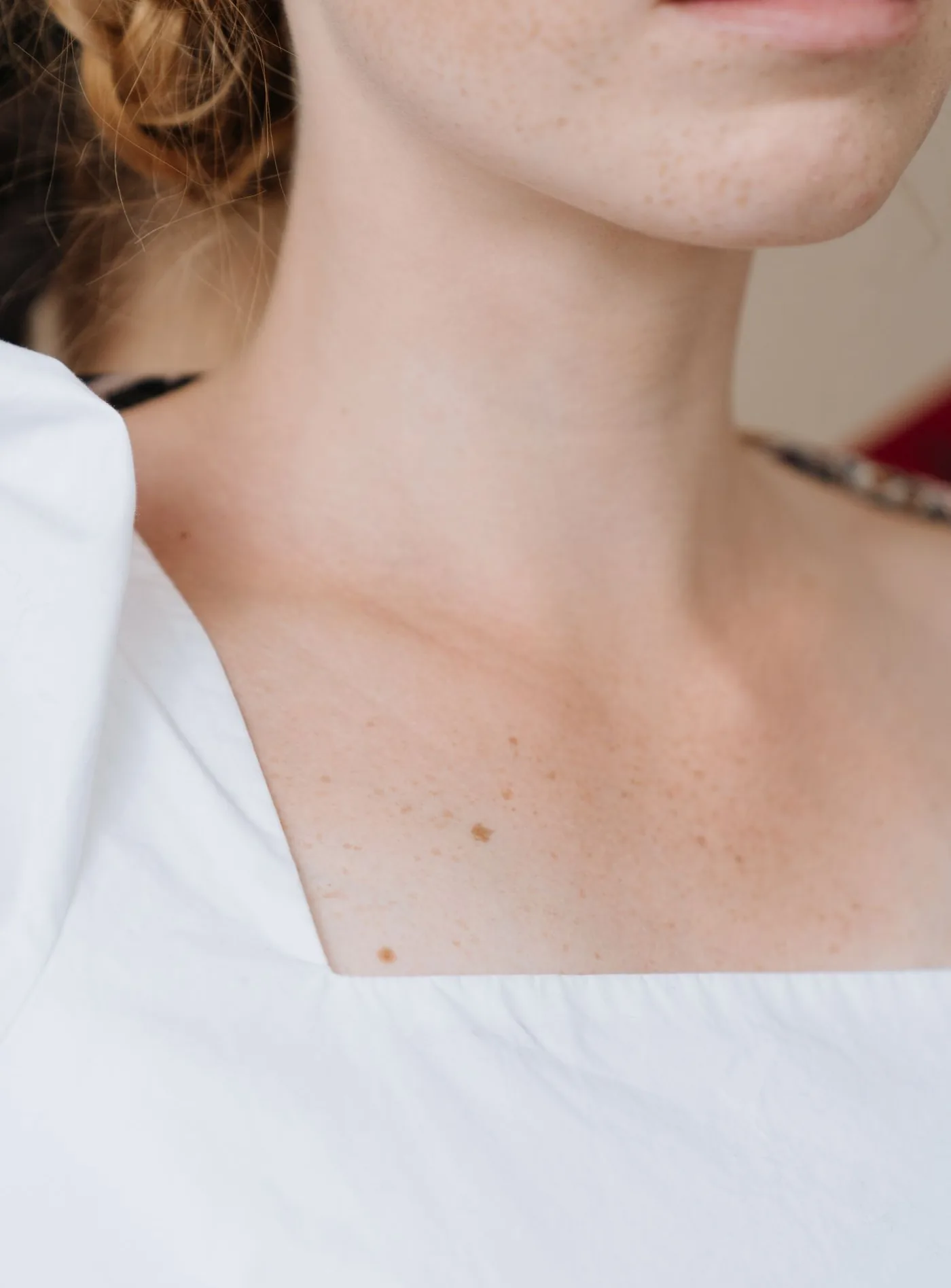 Hals und Dekolleté einer Frau in weißer Bluse mit glatter Haut, Modellaufnahme zur Ästhetischen Chirurgie der Brust in Düsseldorf