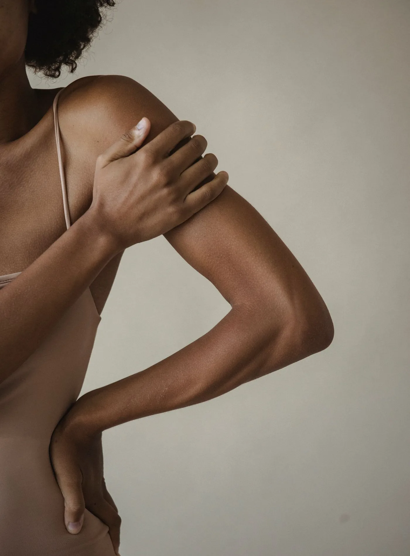 Oberarm und Schulter einer Frau, die Hand umfasst den Oberarm, Modellaufnahme zur Arm und Beinstraffung in Düsseldorf