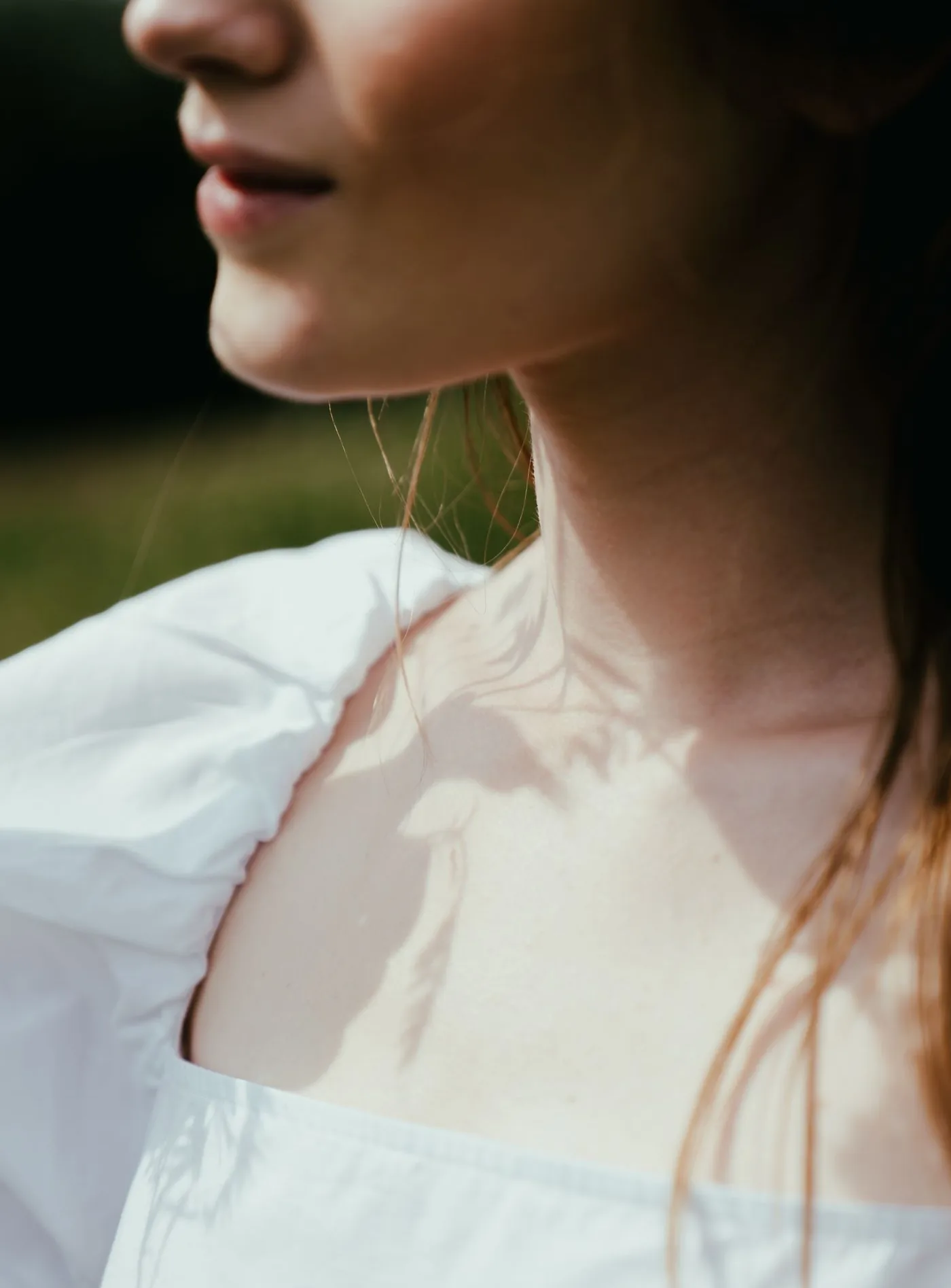 Hals und Schulterpartie in weißer Bluse im Sonnenlicht, Modellaufnahme zum Implantatwechsel in Düsseldorf