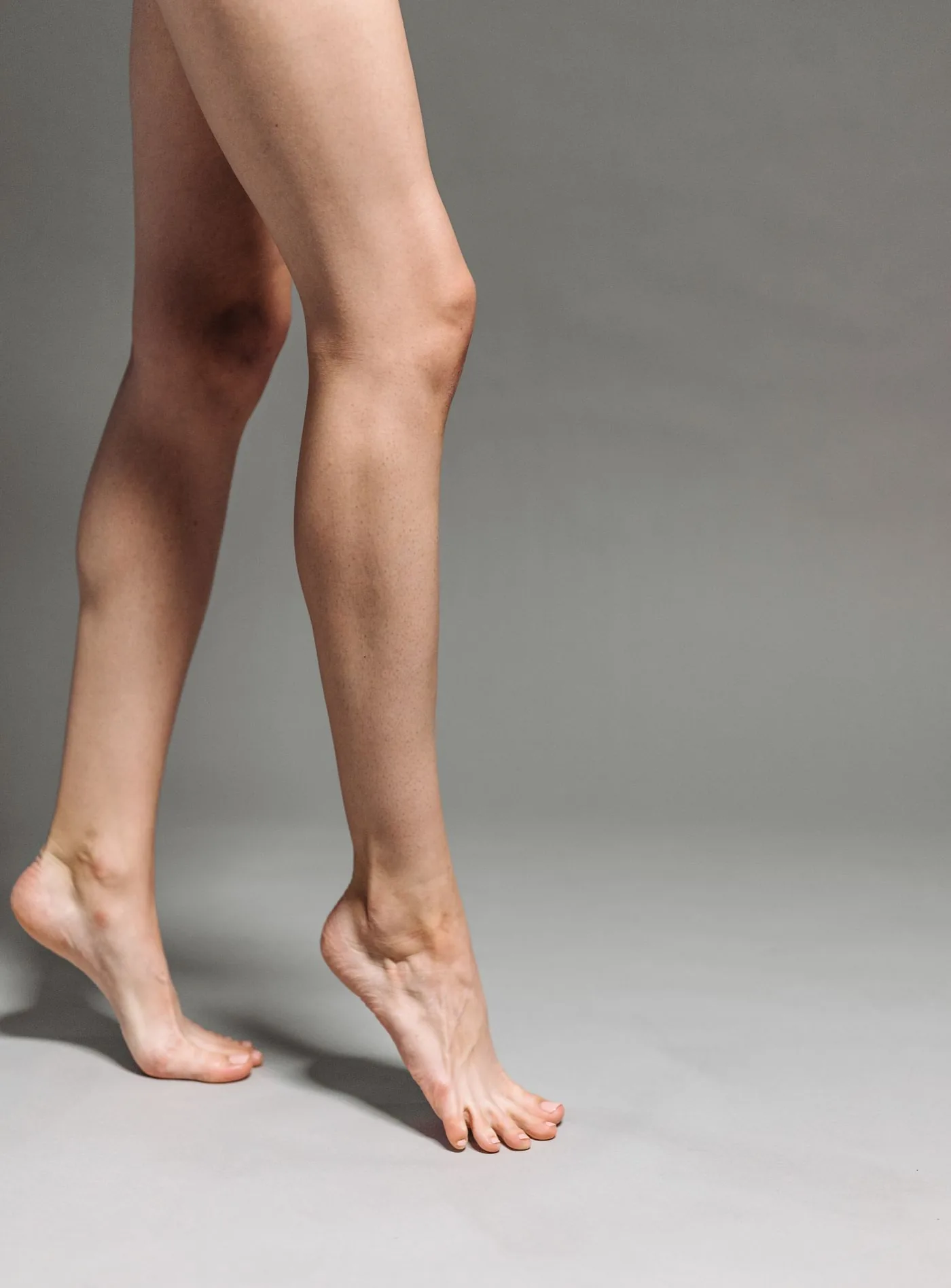Schlanke Beine im Schritt vor grauem Hintergrund, Modellaufnahme zur Arm und Beinstraffung in Düsseldorf