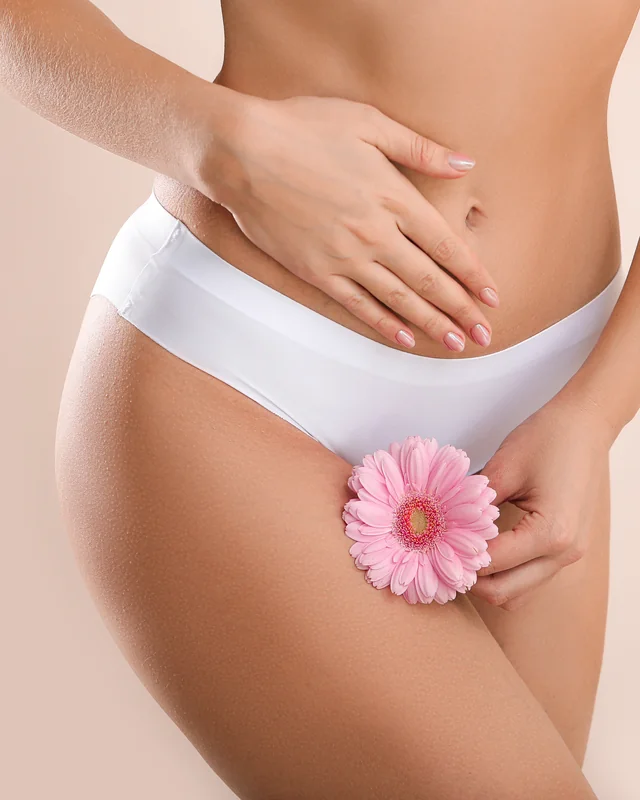 Frau in weißer Unterwäsche mit rosa Gerbera, dezentes Motiv zum Bereich Intimchirurgie, Düsseldorf