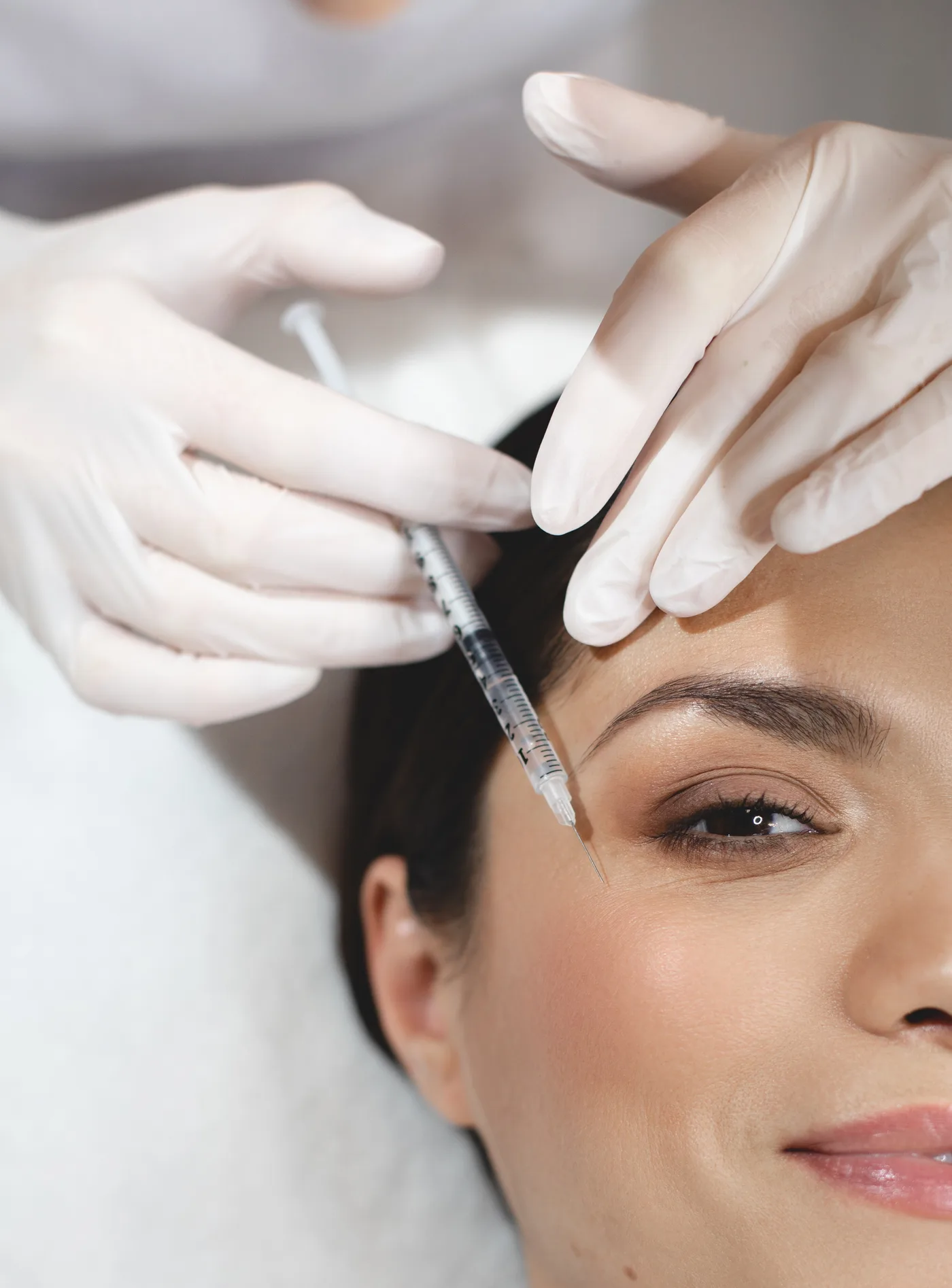Injektion mit feiner Spritze an der Schläfe, Hände in Handschuhen, Modellaufnahme zur PRP Therapie (Eigenblutbehandlung) in Düsseldorf